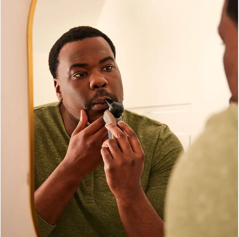 Man shaving with a Remington X9 rotary shaver in front of a mirror